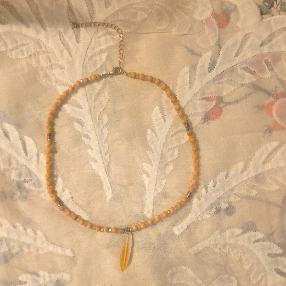 Tan Beaded Necklace With Embellishments Including A Shell Like Fearher.